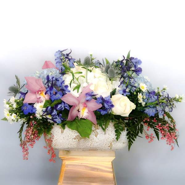 Mixed floral arrangement in a stone planter with pink orchids and white roses
