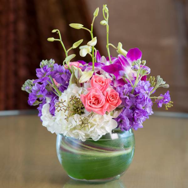 Pink roses and purple orchids in a glass vase