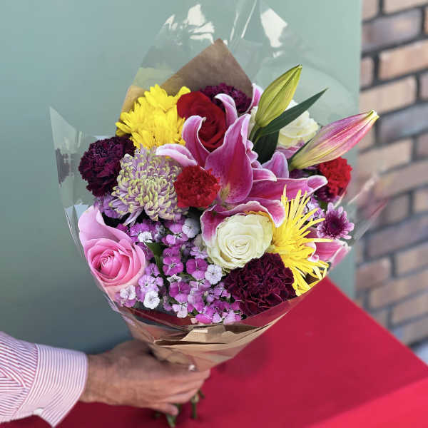 Handheld bouquet of mixed pink, yellow, white, and red flowers