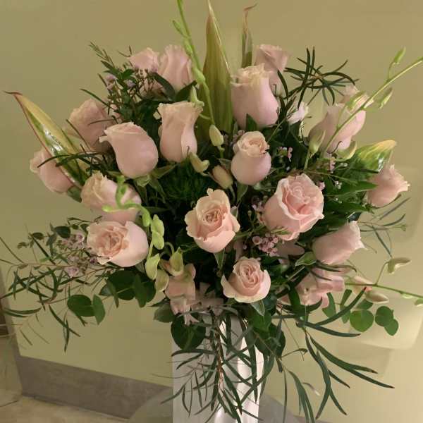 Pink roses arranged in a white vase with greenery