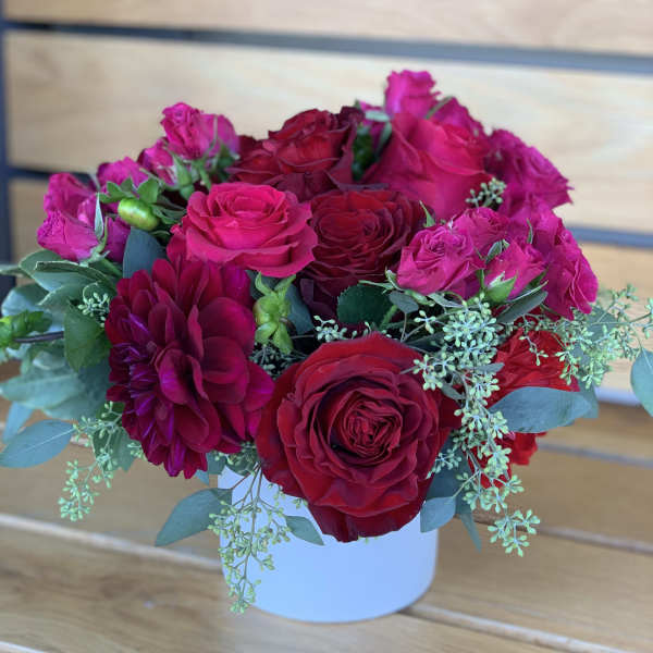 Bouquet of red and pink roses with a burgundy dahlia in a white vase