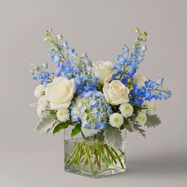 Blue and white floral arrangement in a clear square vase