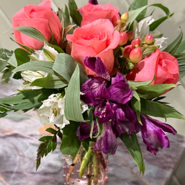 Pink roses and purple flowers in a glass vase