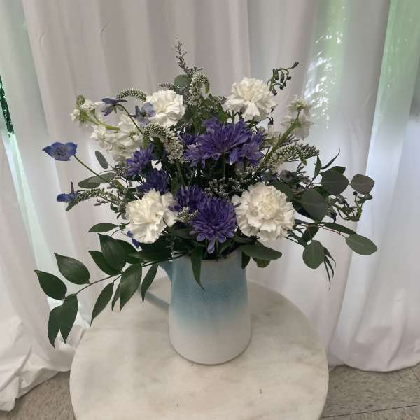 Purple and white flowers arranged in a blue vase