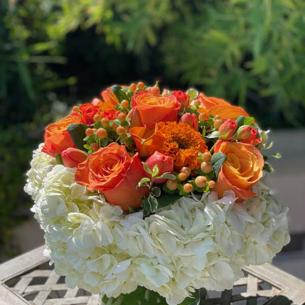 Orange roses and white hydrangeas in a clear glass vase
