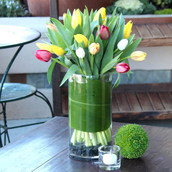 Tulip bouquet in a clear glass vase with a green wrap