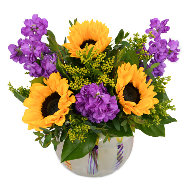 Sunflowers and purple flowers arranged in a glass vase
