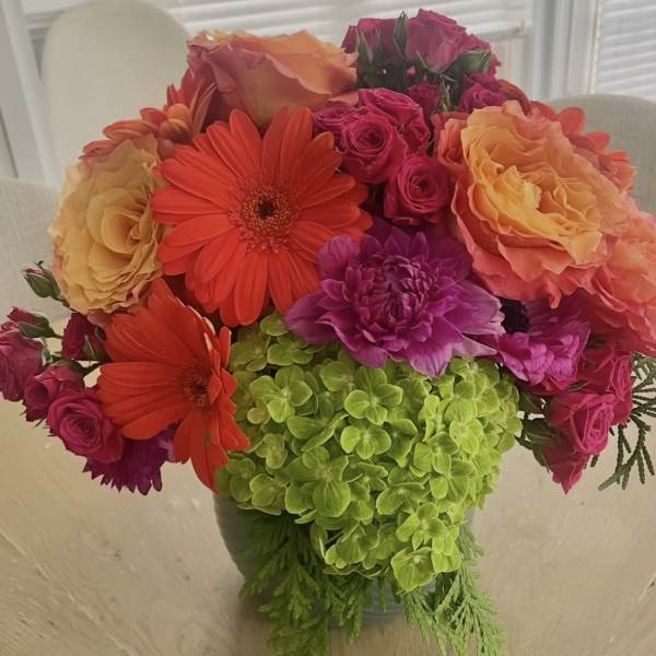 Bright mixed bouquet with roses, gerbera daisies, and green hydrangea in a vase