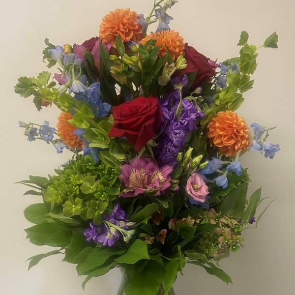 Mixed bouquet in a glass vase with red, orange, purple, and blue flowers