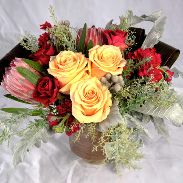 Bouquet of yellow and red roses with protea in a vase
