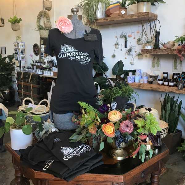 Floral arrangement on a table beside a mannequin wearing a black T-shirt.