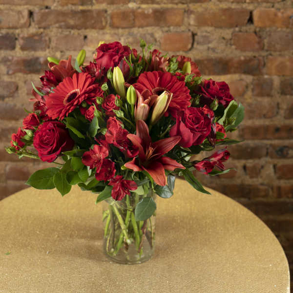 Red mixed flower bouquet in a clear glass vase
