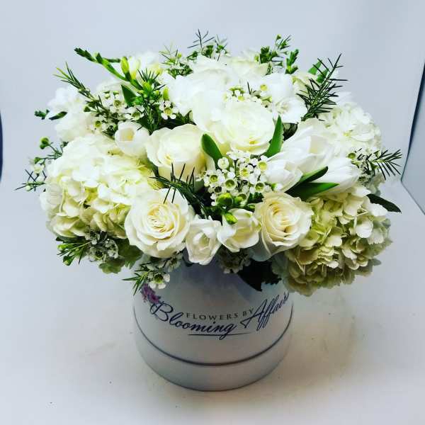 White roses and hydrangeas arranged in a round hatbox
