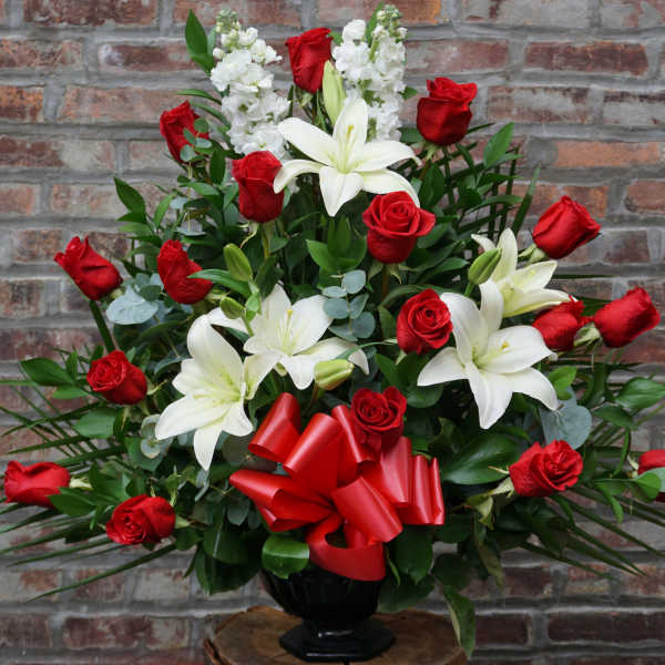 Red roses and white lilies in a black vase with a red bow