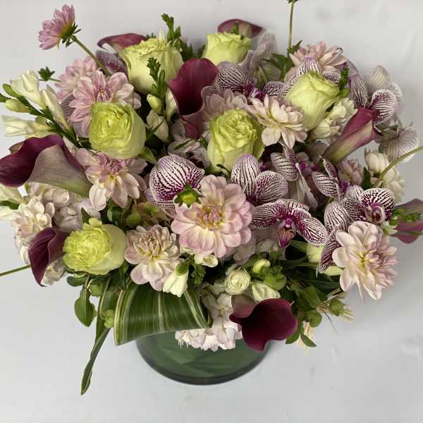 Mixed bouquet of pale pink and green flowers in a glass vase