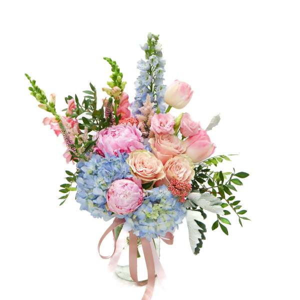 Pastel bouquet of roses, peonies, hydrangeas, and snapdragons in a glass vase