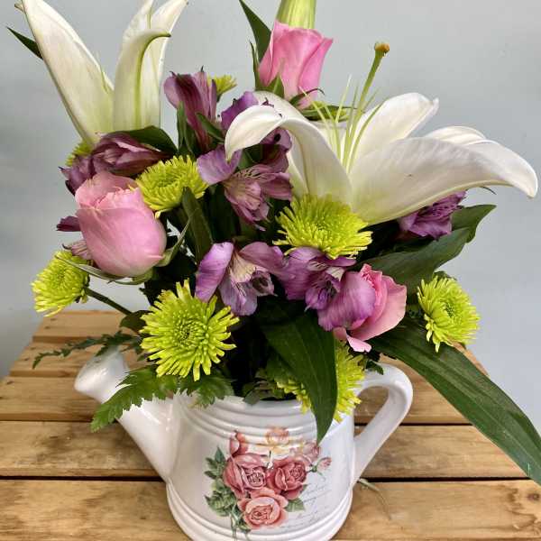 Pink and white flowers arranged in a white teapot vase