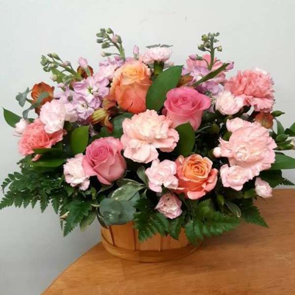 Pink and peach rose bouquet with carnations in a wooden basket