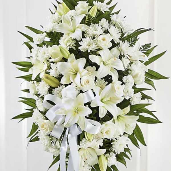White funeral spray with lilies, roses, and chrysanthemums on a stand