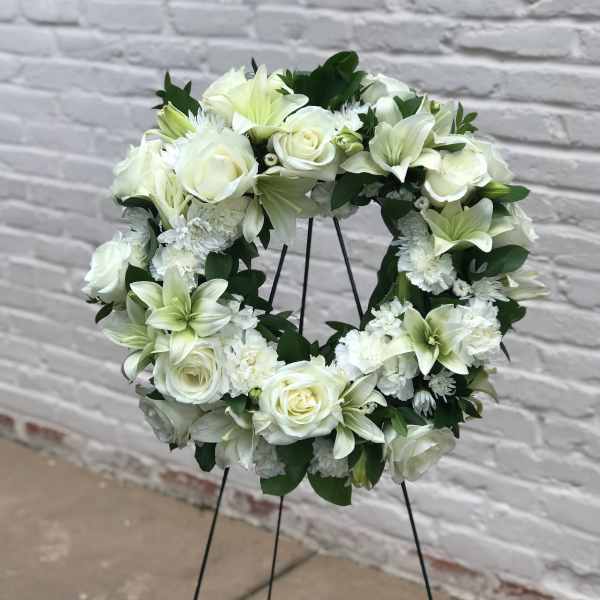 White floral wreath on a black stand