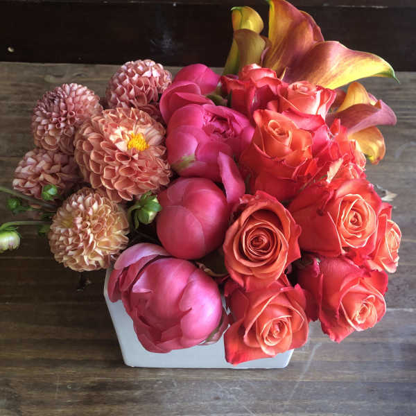 Pink and coral flowers arranged in a white vase