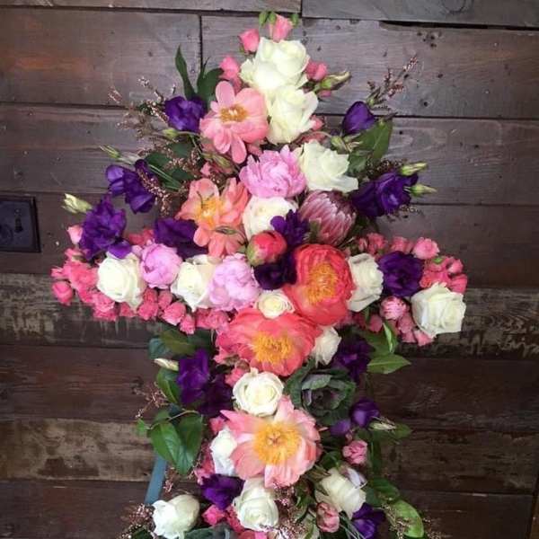 Cross-shaped floral arrangement with pink, white, and purple flowers