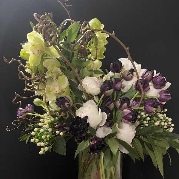 Bouquet of purple and white flowers in a glass vase with curly branches