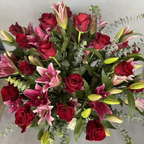 Bouquet of red roses and pink lilies with greenery