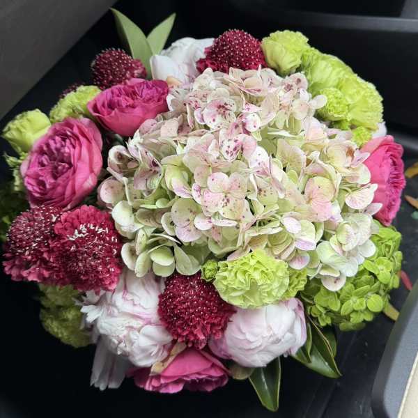 Bouquet of pink and green flowers with a large pale hydrangea cluster