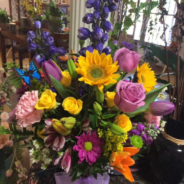 Colorful mixed bouquet in a glass vase with sunflowers, roses, and tulips