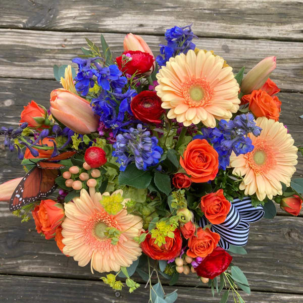 Colorful bouquet with gerbera daisies, roses, and blue flowers