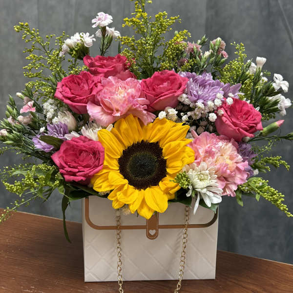 Mixed bouquet with a sunflower, pink roses, and pastel flowers in a gift box