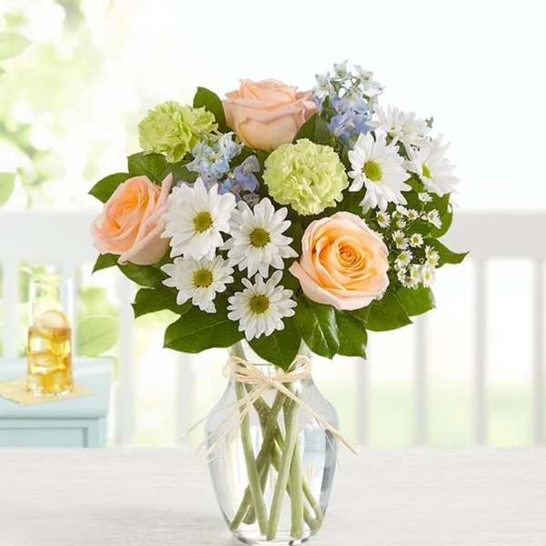 Peach roses and white daisies in a clear glass vase