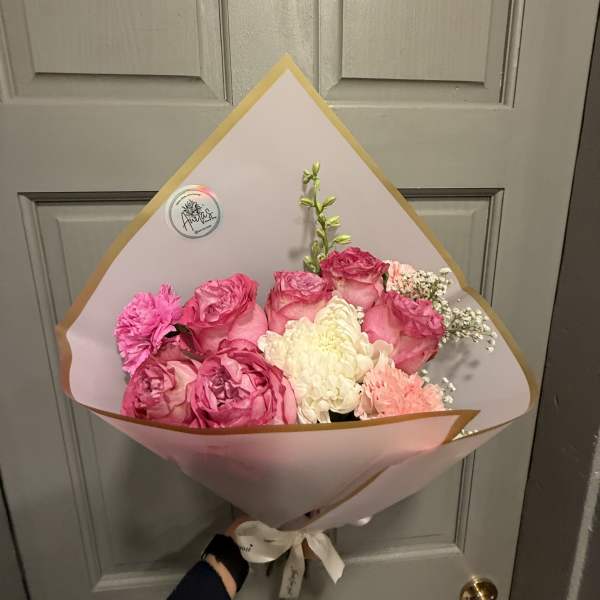 Pink and white bouquet of roses and carnations wrapped in pastel paper