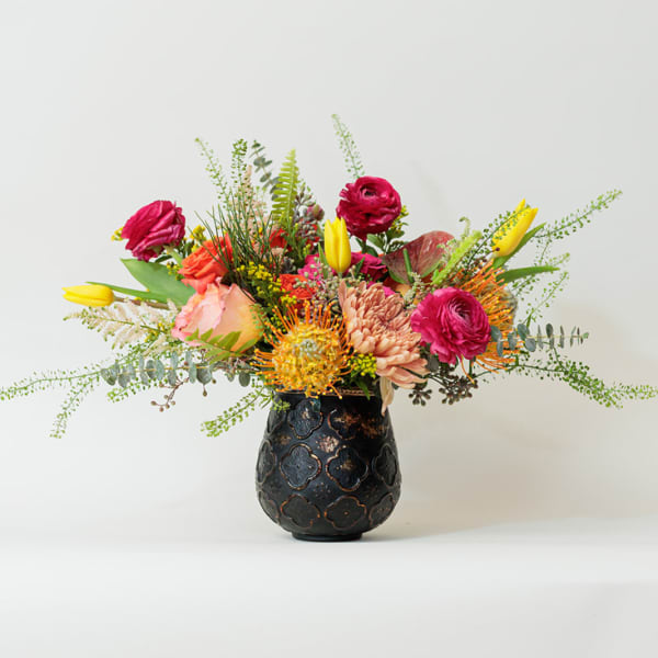 Colorful mixed flower arrangement in a dark decorative vase