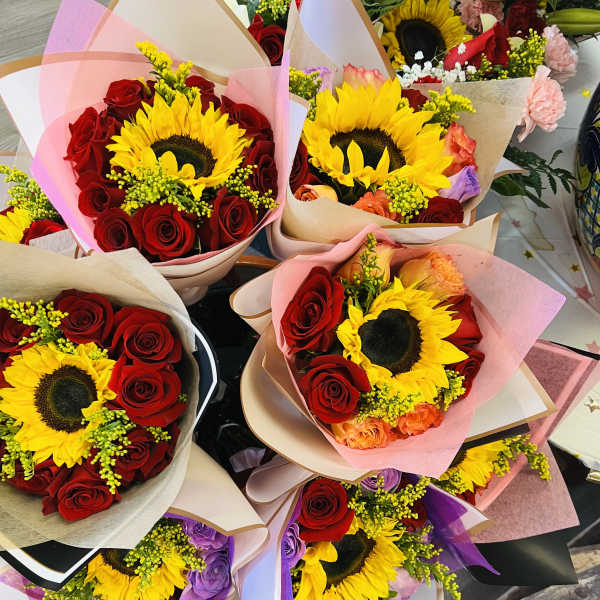 Bouquets of sunflowers and red roses wrapped in pastel paper