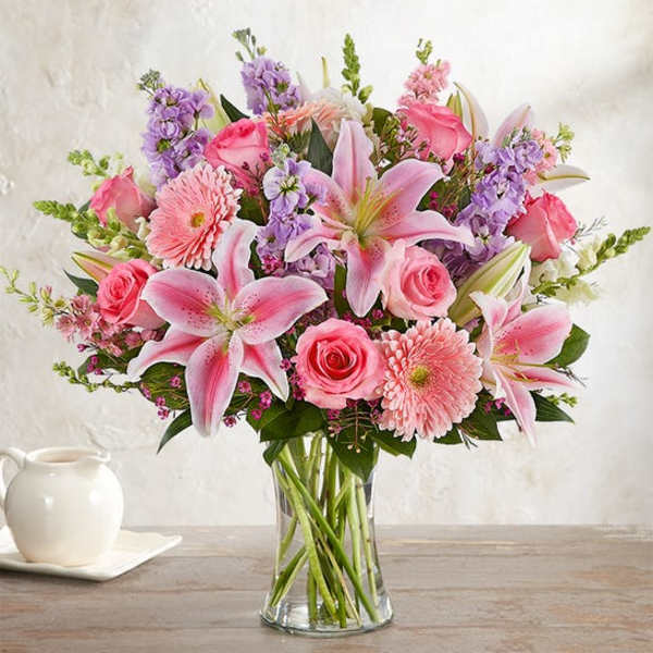 Pink lilies, roses, and daisies in a clear glass vase