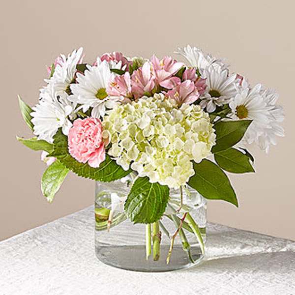 Pink and white flowers arranged in a clear glass vase