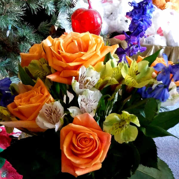 Orange roses and mixed lilies in a glass vase
