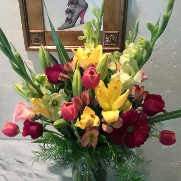 Mixed bouquet of lilies, tulips, and roses in a glass vase