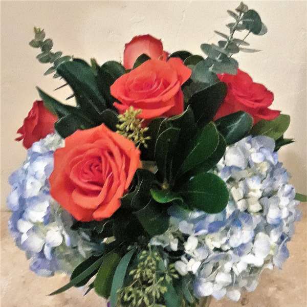 Bouquet of coral roses and pale blue hydrangeas in a glass vase