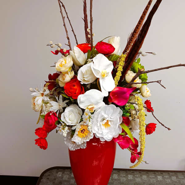 Red vase with a mixed bouquet of white, red, and pink flowers