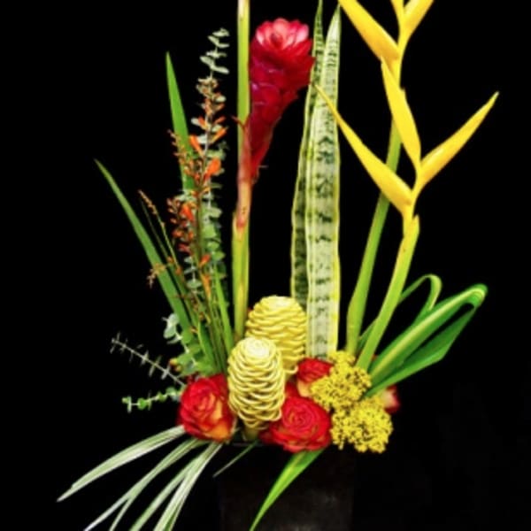 Tall tropical arrangement with red ginger, yellow heliconia, and roses in a black rectangular container.