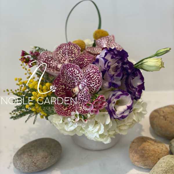 Purple orchids and white hydrangeas in a white basket