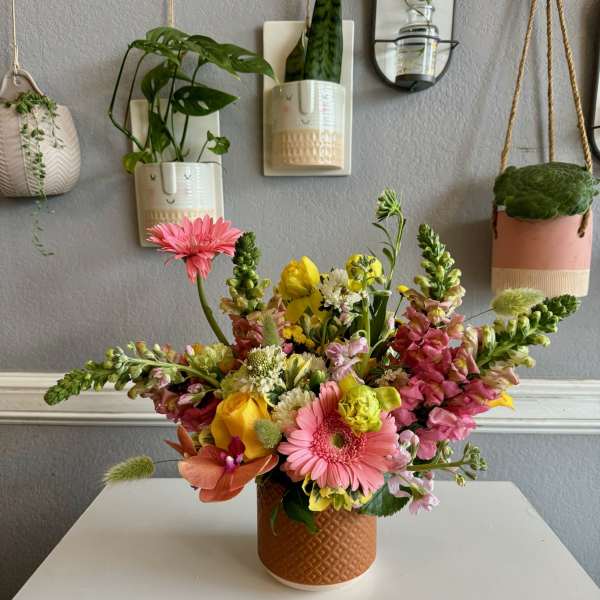 Colorful mixed flower arrangement in a textured brown vase