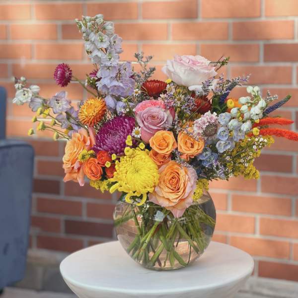Mixed bouquet of roses, chrysanthemums, and delphinium in a glass vase