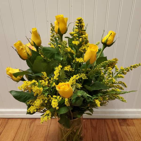 Tall arrangement of yellow roses with yellow filler in a clear glass vase