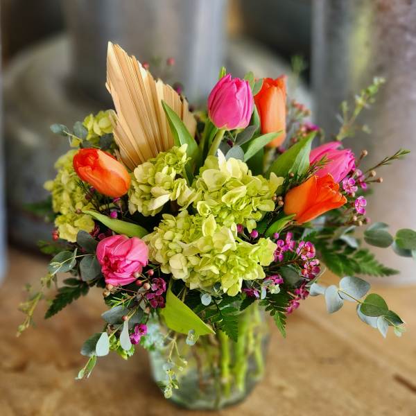 Bouquet of pink and orange tulips with green hydrangeas in a glass vase
