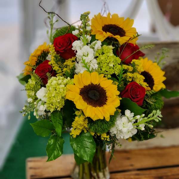 Bouquet of red roses and yellow sunflowers in a glass vase