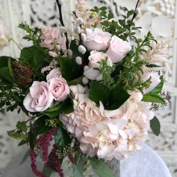Pink roses and hydrangea in a glass vase with greenery
